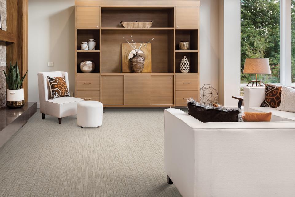 grey textured carpet in living room with white couch and wooden furniture.